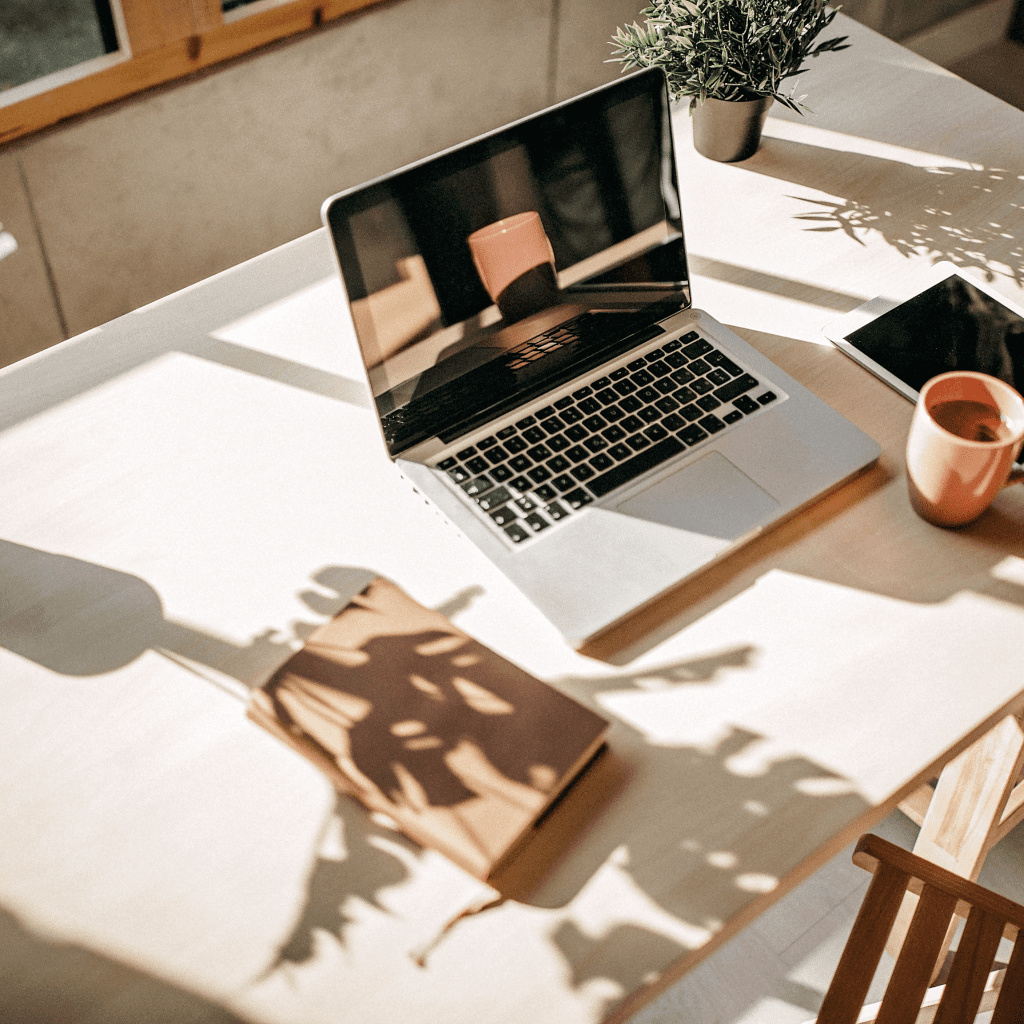 Schreibtisch mit Laptop, Kaffee, iPad und Notizbuch